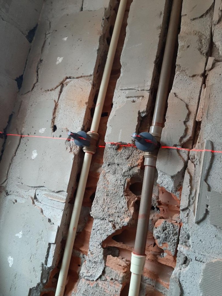Tubulação hidráulica alinhada com nível a laser em obra